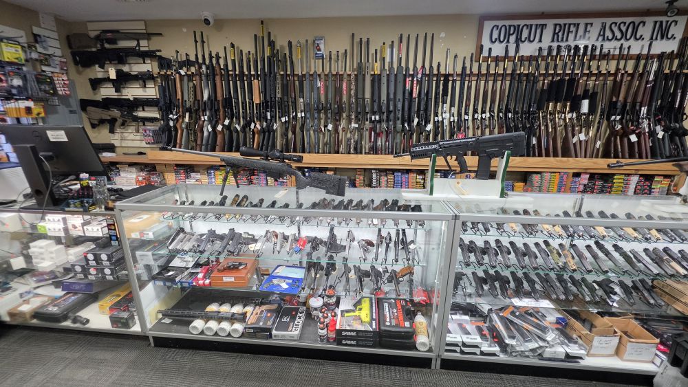 Handgun display cases at Village Sports, with rifles on the wall behind
